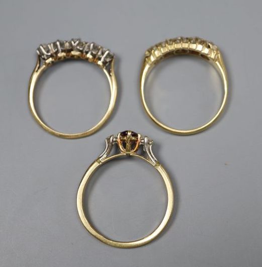 An 18ct gold, garnet? and diamond three stone ring and two yellow metal and five stone diamond half hoop rings, gross 8.4 grams.